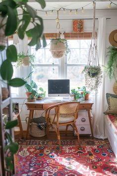 a desk with a laptop on it in front of a window filled with potted plants