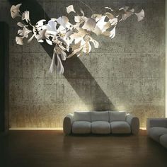 a living room filled with furniture next to a wall covered in paper flowers and leaves