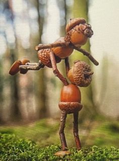 a small wooden figure standing in the middle of a forest filled with green grass and mushrooms