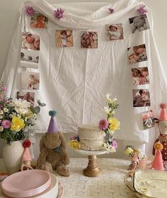 a table topped with lots of cake next to pictures on the wall and flowers in vases