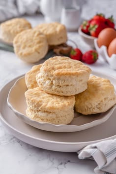 three biscuits on a plate with strawberries and eggs in the backgroung