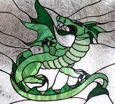 a stained glass window with a green dragon on it's body and wings, in front of a white background