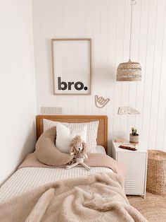 a bedroom with white walls and beige bed linens, a brown teddy bear sitting on the pillow