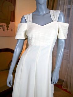 a mannequin wearing a white dress in front of a window