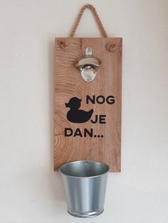 a wooden sign hanging on the side of a wall with a metal cup next to it