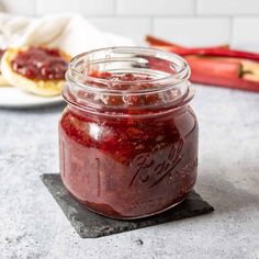 a glass jar filled with jam sitting on top of a table next to a spoon