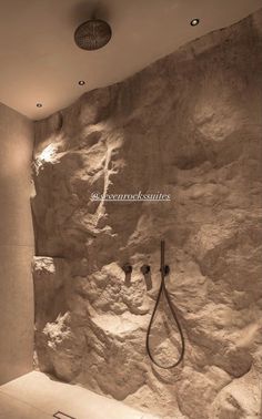 a bathroom with stone walls and a shower head in the corner, next to a sink