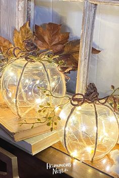 two glass pumpkins with lights on them sitting on a table next to an old window