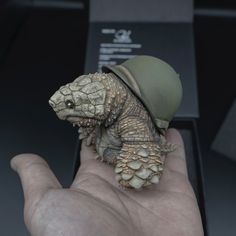 a hand holding a small turtle with a hat on it's head in front of a display case