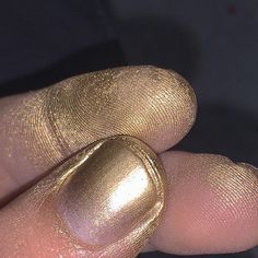 a person's finger with gold nail polish on it