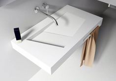 a white sink sitting next to a towel rack on top of a bathroom counter under a faucet