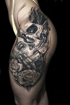 a woman's thigh with a skull and roses tattoo on it