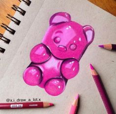 a drawing of a pink teddy bear on top of a piece of paper with colored pencils next to it