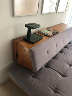 a couch with a phone on top of it in front of two framed pictures hanging on the wall