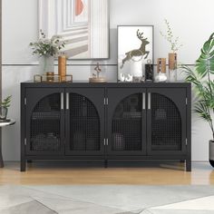 a living room with a large black cabinet and plants on the sideboard next to it