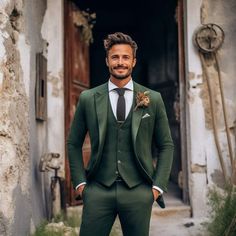 a man wearing a green suit and tie standing in front of an old building with his hands in his pockets