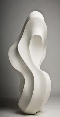 a white sculpture sitting on top of a table next to a gray wall and floor