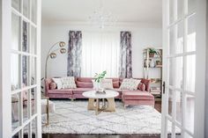 a living room filled with furniture and a chandelier hanging from the ceiling over a white rug