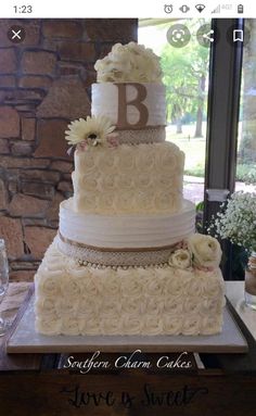 a three tiered wedding cake with white flowers on the bottom and monogrammed b