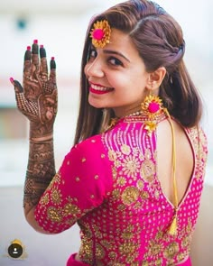 a woman in a pink dress holding her hands up to show the henna on her hand