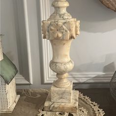 a white marble vase sitting on top of a table next to a clock and other items