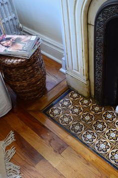 a dog laying on the floor next to a fire place with magazines and a basket