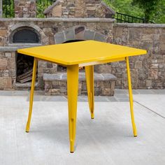 an orange table sitting on top of a cement floor next to a brick wall and fire place