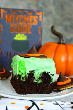 a piece of cake with green frosting on a plate next to two pumpkins