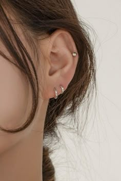 a woman's ear is shown with two piercings on the top of it