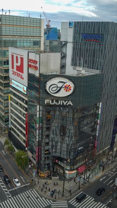 an aerial view of a large building with many signs on it's sides and people crossing the street