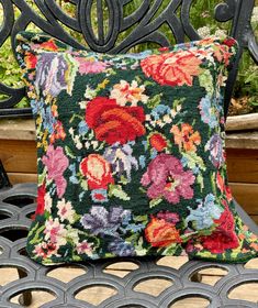 a floral pillow sitting on top of a metal bench