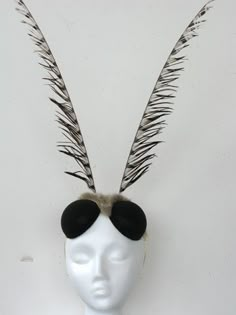 a white mannequin head with feathers and sunglasses on it's headpiece