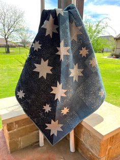 a blue and white towel with stars on it hanging from a wooden post in front of a house