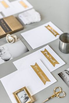 a table topped with lots of pictures and gold accents on top of white paper next to a metal cup