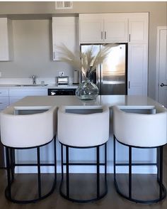 three white stools sit at the center of a kitchen island