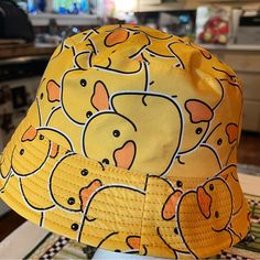 a yellow hat with cartoon animals on it sitting on top of a table in a kitchen