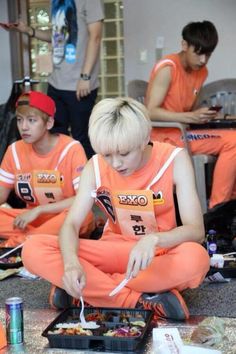 the group of young men are sitting on the floor with food in front of them