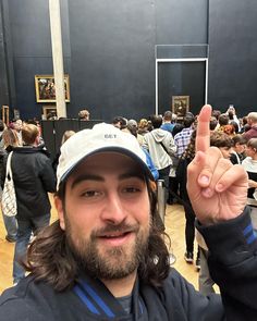 a man with long hair wearing a hat and holding up a peace sign