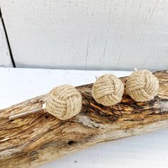 two roped knot earrings sitting on top of a piece of driftwood