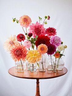 a wooden table topped with lots of vases filled with flowers on top of it