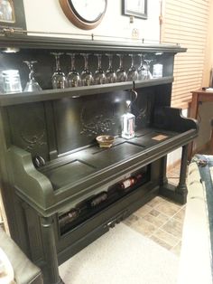 an old fashioned stove with wine glasses on it's top and bottom shelf in a living room