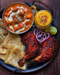 a plate full of food including chicken, tortillas and salsas on the side