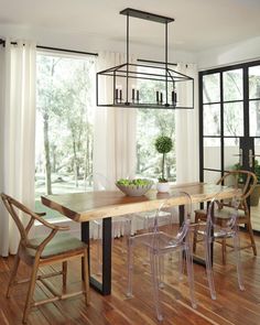 a dining room table with clear chairs and a light fixture hanging over it's head