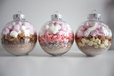 three glass ornaments filled with candy and marshmallows