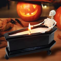 a skeleton sitting in a candle holder on a table with jack - o'- lanterns