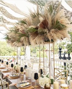 an outdoor dining area with tables, candles and flowers on the table in front of it