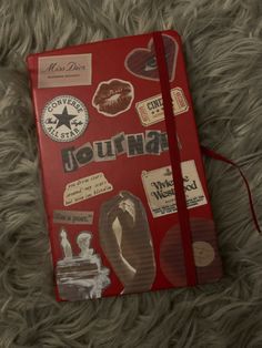 a red journal covered in stickers and magnets sitting on top of a furry surface