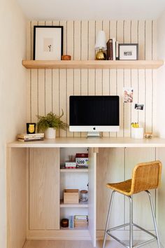 a desk with a computer on top of it next to a chair and bookshelf