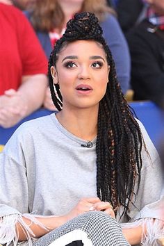 a woman with long braids sitting in front of a crowd