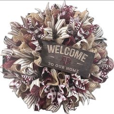 a welcome sign hanging from the side of a wreath with ribbons on it's sides